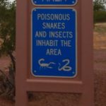 Close-up of sign waring of poisonous snakes and insects in area