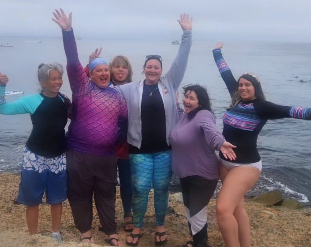 Group of women posing celebrating on beach