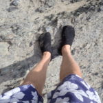 Ken's feet wearing slippers on rough rock