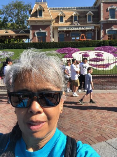 Cathy standing in front of purple & white flower art of Mickey Mouse
